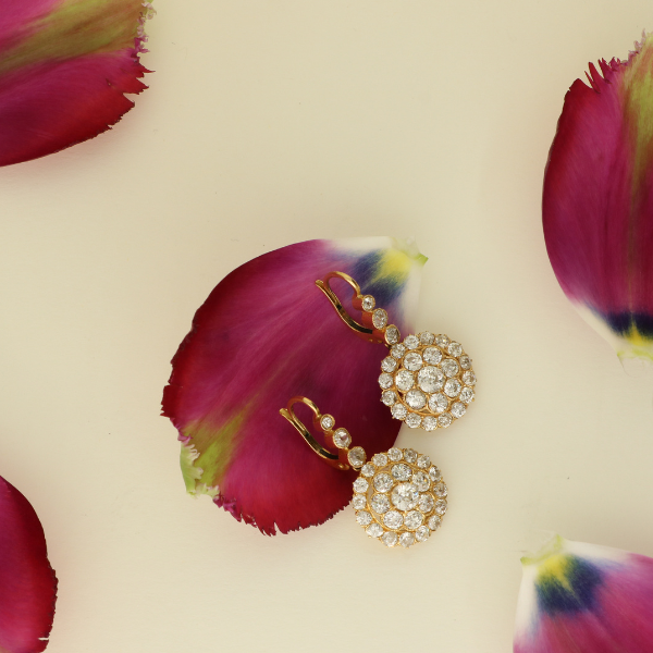 Gold earrings on pink flower petals with a beige background