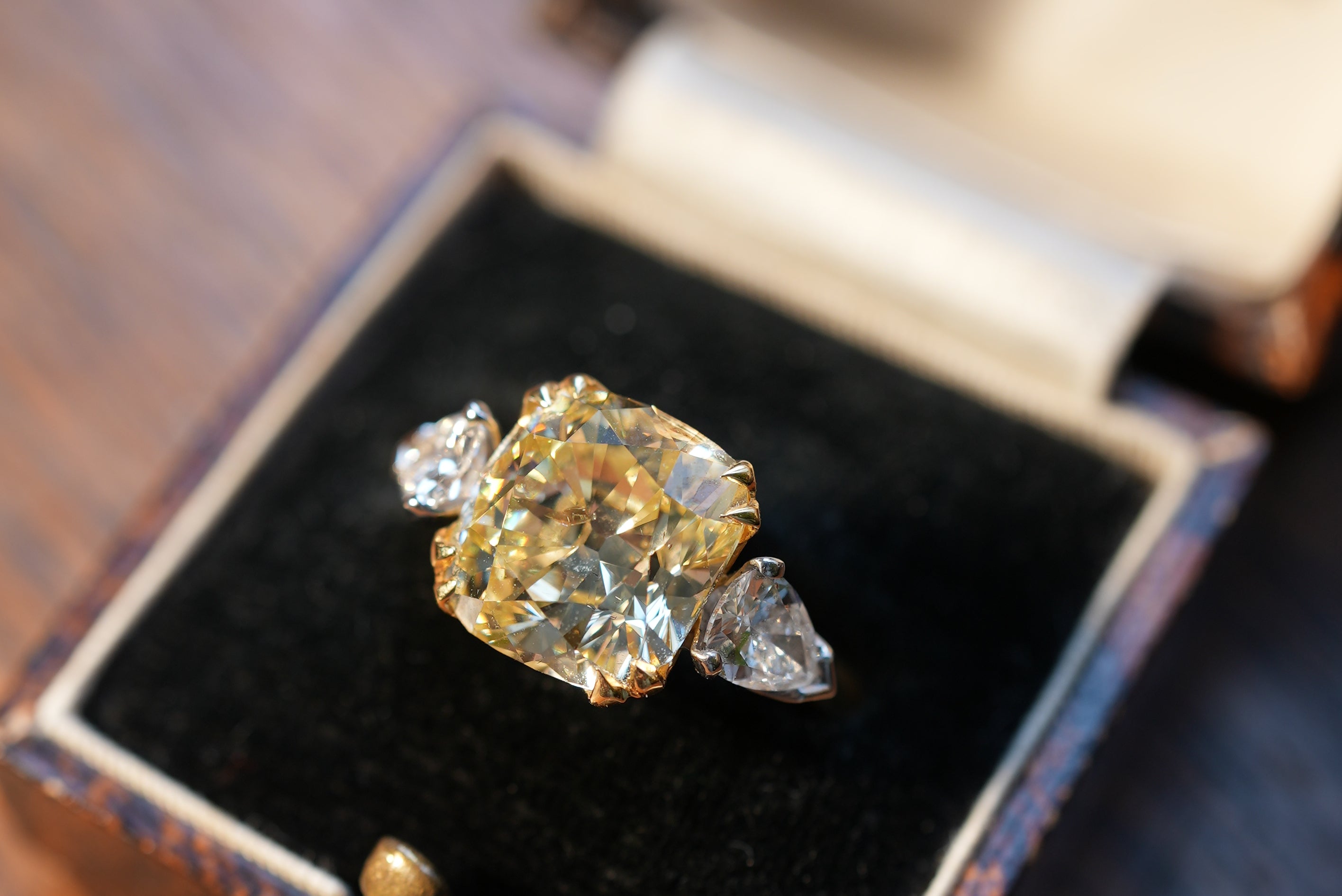 Diamond ring in an open jewelry box on a wooden surface
