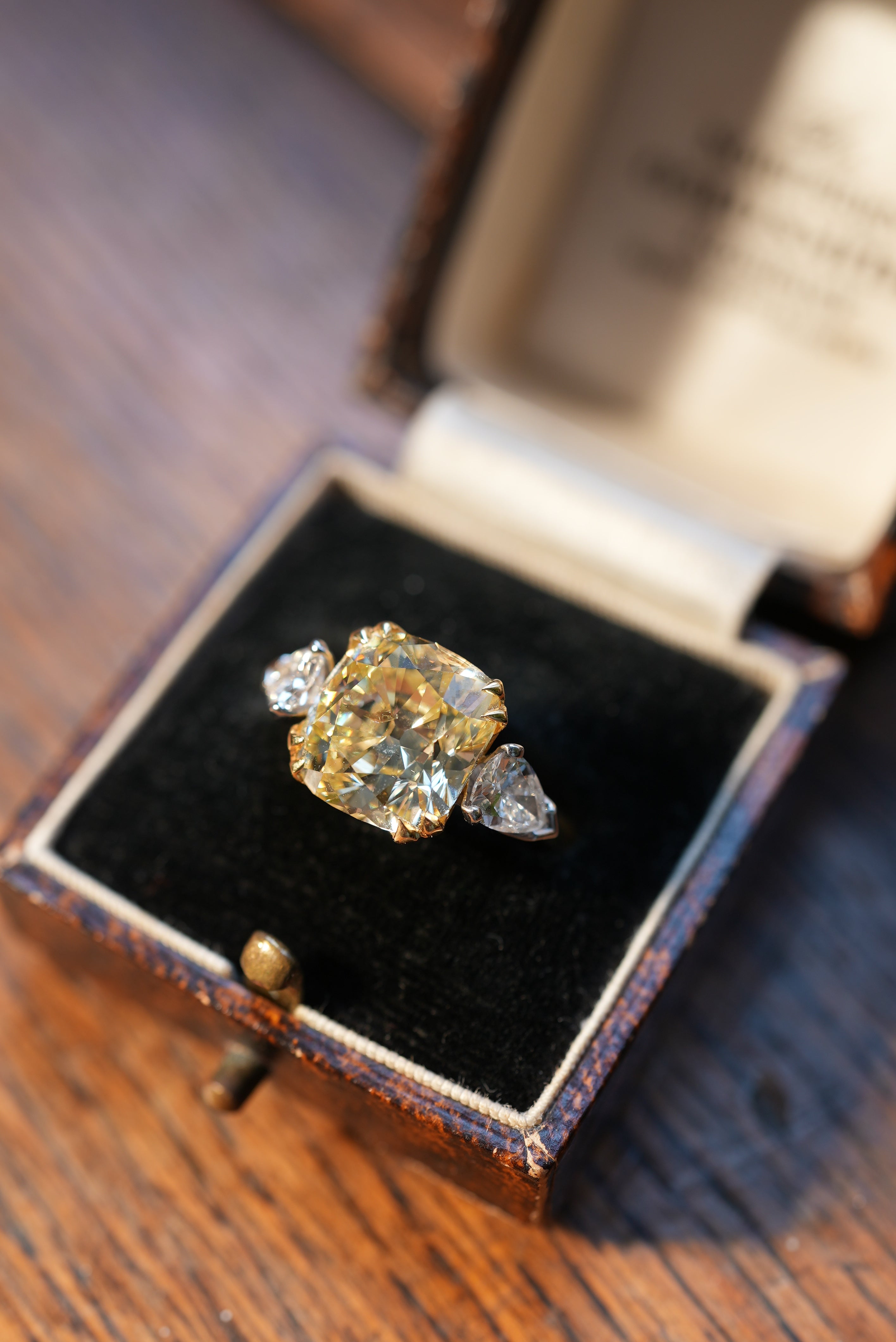 Diamond ring in an open jewelry box on a wooden surface